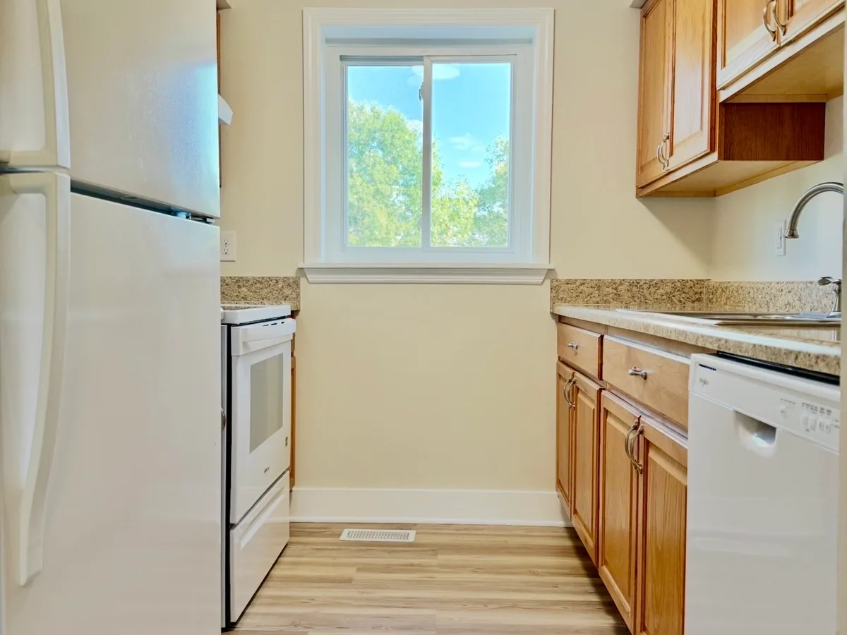 After: galley kitchen with oak cabinets, going from a dated worn floor and dingy walls to bright walls and new wood-look flooring