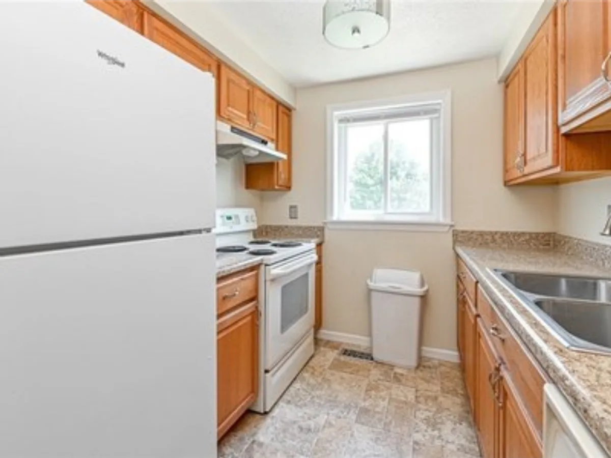 Before: galley kitchen with oak cabinets, going from a dated worn floor and dingy walls to bright walls and new wood-look flooring
