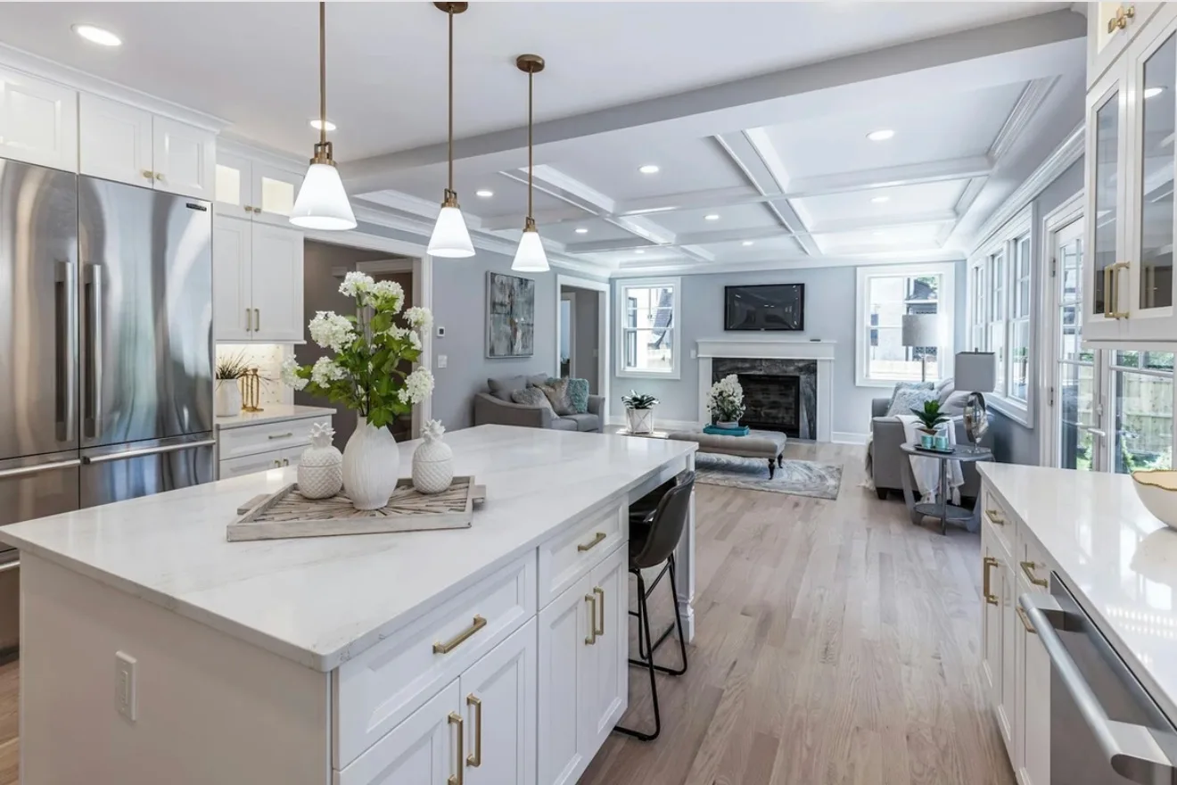 Bright open-concept kitchen and living room with a white quartz island, gold hardware, and hardwood floors, detailed after construction by Maid With Precision