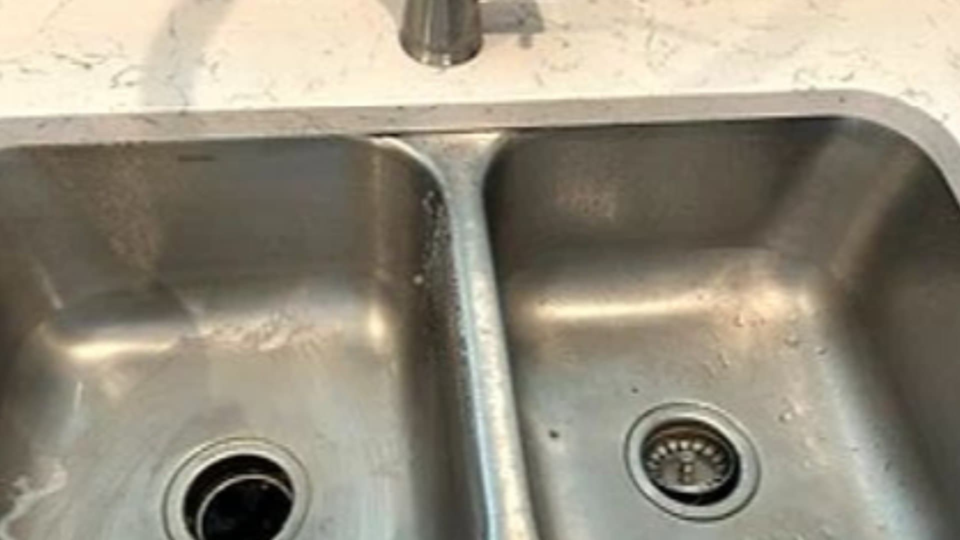 A dull, water-spotted stainless steel kitchen sink before cleaning